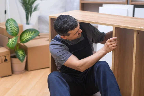 Skilled Craftsman Assembling and Repairing Furniture in blue uniform for a Beautifully Furnished Home. Handyman service professional