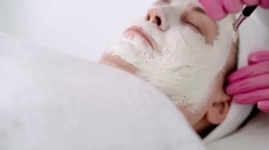 Kozmetik uzmanlarının ellerini pembe eldivenlerle kapat ve yüz güzelliği maskesi tak..