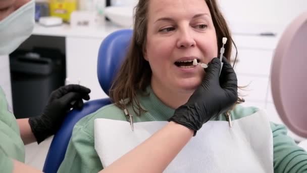 持有牙齿颜色样本的医生帮助病人处理牙齿表面及美白 — 图库视频影像