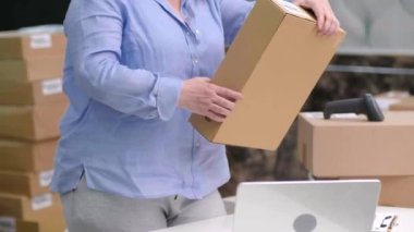 Kadın girişimci ev ofisine nakliye için bir paket hazırlıyor. E-ticaret çevrimiçi sipariş teslimat lojistik servis kavramı