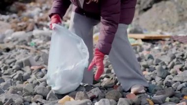 Çevreyi korumak için birlikte çalışan gönüllüler, kirlenmiş bir plajı temizlerken, sürdürülebilirlik ve ekolojik sorumluluğu desteklerken plastik çöp ve atık topluyorlar.