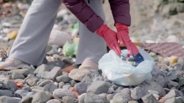 Kadın elleri, özellikle kumlu sahilde dökülen çöpleri, özellikle boş, kirli plastik şişeleri toplar. önemli ekolojik problem