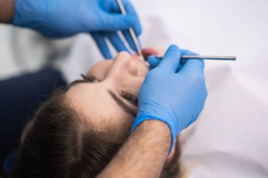 Modern diş hekimliği kliniğinde kauçuk eldivenli diş tedavisi. Kadın hastaların profesyonel diş muayenesi için çalışan kadınların yakın çekim boşluklarını kontrol ediyor.