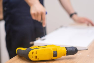 Mobilya montajı ustası elektrikli tornavida yüksek kaliteli marangozluk işiyle tahta rafa çivi çakıyor.