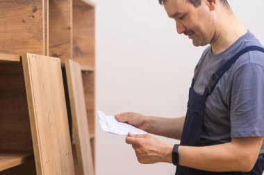 Mobilya nakliyesi ve tamiratı, ahşap askı montaj uzmanının müşteri dairesinde mobilya teslimatı ve inşaatı talimatlarını okumaya odaklandı.