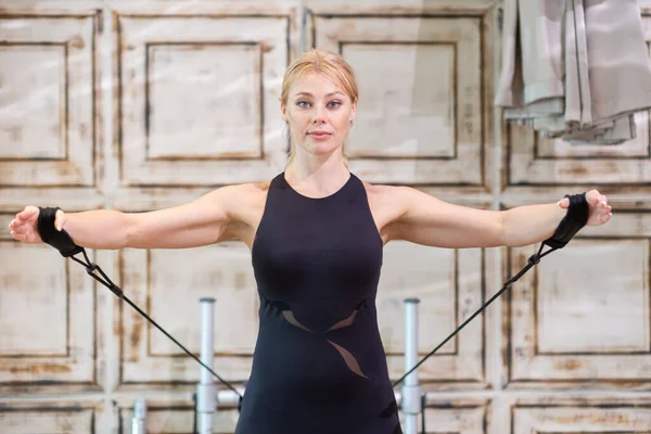 stock image Intensive pilates training at class female coach showing stretching exercises on reformer blonde woman in black sportswear enjoying sports activity in modern studio