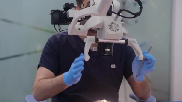 女性の歯を詳細に見るためにプロの機器を使用して 患者の虫歯に焦点を当てた歯科医の検査のための革新的な歯科顕微鏡現代の歯科クリニックでの定期的な衛生ケア — ストック動画