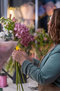 Çiçekçiler yetenekli çiçekçiler, genç bir kadın, baş döndürücü buketler yaratıyor, sonra da makasla kesilmiş çiçekleri ustalıkla hazırlıyor..