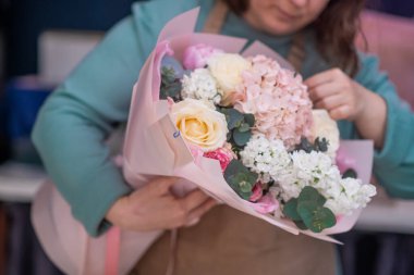 Çiçekçide çalışan çalışkan bir çiçekçi çiçek teslimatı için siparişleri kabul eder ve her durum için mükemmel düzenlemeler yapar. 