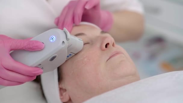 女性のクライアントは プロの機器を使用して美容センターで癒しのSmas超音波顔リフティングマッサージを取得します 顔を閉じて — ストック動画