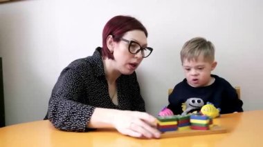 Down sendromlu şirin bir çocuk ve öğretmeniyle birlikte geliştirilen eğitim programlarına dahil olan gelişimsel engelliler. Zihinsel ve fiziksel sağlık için rehabilitasyon oyunları. 