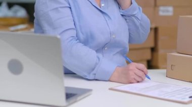 Depoda çalışırken dizüstü bilgisayar kullanarak bir çevrimiçi mağaza işletiyor ve depoda envanter yönetiyor. Ekspres nakliye