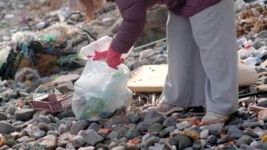 Çevreyi korumak için birlikte çalışan gönüllüler, kirlenmiş bir plajı temizlerken, sürdürülebilirlik ve ekolojik sorumluluğu desteklerken, plastik çöp topluyorlar.