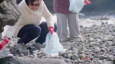 Bir grup gönüllü, çevreyi korumak ve deniz hayatını korumak amacıyla kirli bir plajı plastik çöplerle temizliyor.