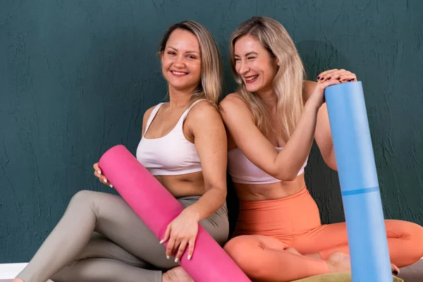 Amigos Femininos Positivos Sportswear Segurando Tapetes Coloridos Sentados Chão Olhando — Fotografia de Stock