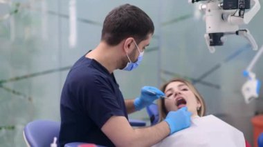 Modern klinikte diş sağlığı uzmanı kadın hastaların dişlerini incelemek için uzman uzmanlar tarafından ısırık düzeltme için hazırlanıyor.