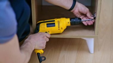 Mobilya kurulumunu kapat becerikli tamirci, dolaptaki yüksek kaliteli ahşap malzemelerden yapılmış kapı perdelerini takıyor, profesyonel mobilyaları tornavidayla birleştiriyor.