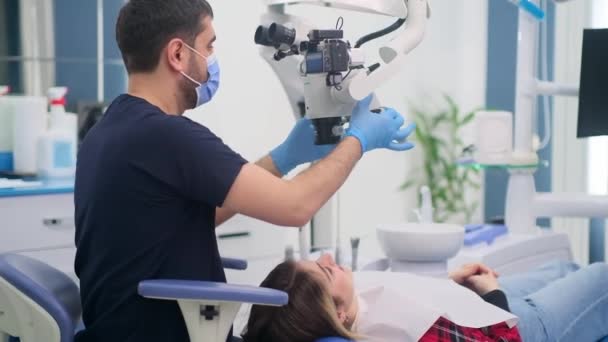 Uppmärksam Tandläkare Tittar Tänder Unga Kvinna Genom Moderna Dentala Mikroskop — Stockvideo