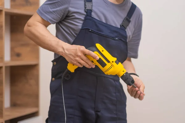Professional handyman assembling a wooden rack with electric screwdriver in a residential space
