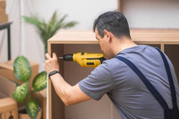 close up Furniture installation skilled handyman attaching door fasteners to cabinet made of high-quality hardwood materials in house professional furniture assembling work with screwdriver
