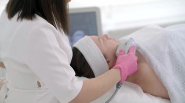 Profesyonel ekipmanlar, güzellik merkezinde rahatlamış bir bayan müşteriye SMAS ultrason yüz kaldırma masajı yapmak için kullanılır.. 