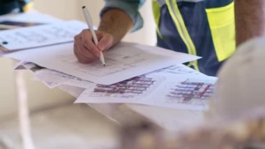 İnşaat malzemelerinin ustalıklı mühendislik tasarısı çizimleri tamamlanmamış oda uzmanı profesyonel tulumlarda ev yenilemeye hazırlanıyor.