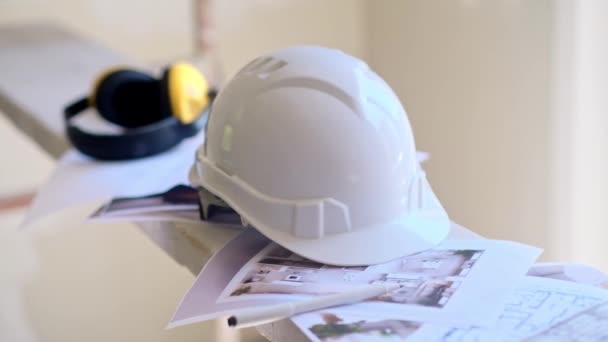 身穿制服 头戴白色防护头盔的熟练工人躺在一堆工程文件上 专人准备对房间建设安全规则和设备进行翻新 — 图库视频影像