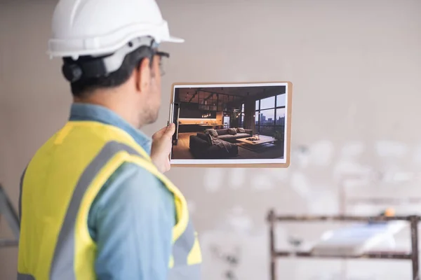 stock image Architect holding picture of project design with modern loft-style interior man in hardhat and vest inspecting premise and imagining living room after renovation