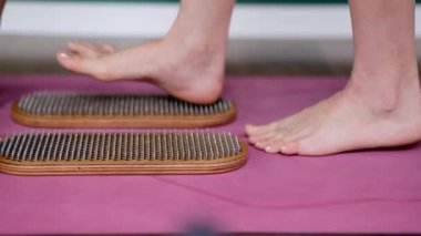Çıplak ayaklı kadın, profesyonel yoga sınıfında çivi refleksototerapisi yapıyor. Sadhu tahtasında kadın ayak, geniş stüdyo etkin vücut gevşeme egzersizleri yapıyor.
