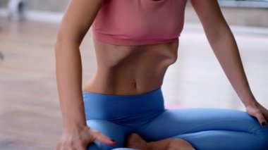  Güzel vücutlu genç bir kadın Uddiyana bandha asana yapıyor yoga yaparken hafif yoga stüdyosunda spor kıyafetleriyle vakum çalışması yapıyor.