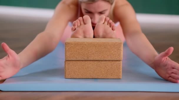 在宽敞的演播室里的职业瑜伽课集中的女人用泡沫块伸展运动的女人在蓝色垫子上做运动 — 图库视频影像