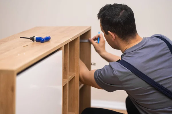 Furniture manufacturing and fixing carpenter hands installing shelves to wooden furniture man using instruments to work with wood in apartment of customer