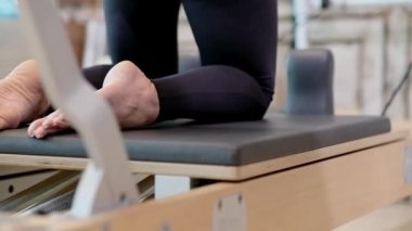 Pilates egzersizi ve vücut bakımı profesyonel koçu modern spor salonunda spor giyim kaslarını güçlendiren formda bir kadın üzerinde etkili bir egzersiz yapıyor.