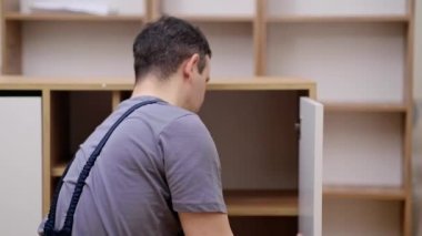 Özel mobilya montajı marangozu ahşap dolap uzmanının kapısını kontrol ediyor. Müşteri dairesinde mobilya montajını bitiriyor.