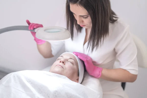 A client at an aesthetic medicine clinic benefits from a skilled cosmetologist facial procedures, including peeling and lifting massages, in a serene spa or salon ambiance.