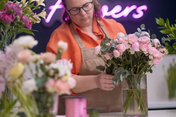love for flowers, the successful female business owner of the flower shop mixing proudly with a gorgeous bouquet of pink roses, a testament to her hard work and dedication.