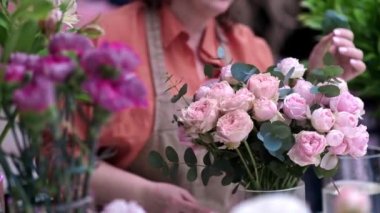 Hassas pembe güller ve şakayıklarla çalışan yetenekli bayan çiçekçi, hem unutulmaz hem de unutulmaz bir düzenleme yapıyor..