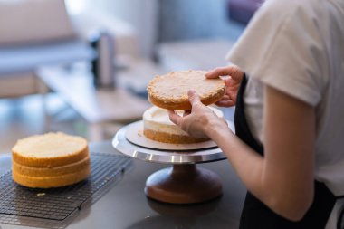 Modern mutfakta organik pasta katmanlarıyla taze beyaz kremayı birleştiren siyah önlüklü pastacı lezzetli hamur işi yakın plan hazırlama sürecinin detaylarını anlattı.
