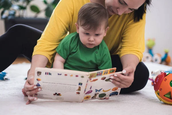 Opiekuńcza Matka Pokazując Skupiony Mały Syn Książka Kolorowe Zdjęcia Żyjących — Zdjęcie stockowe