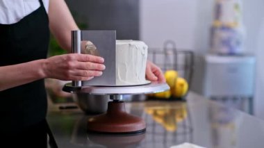 Profesyonel pastacı, pastaya beyaz şekersiz makarna serpiştiriyor. Bıçaklı, önlüklü kadın, mutfakta bekleyen müşteriler için lezzetli organik hamur işleri yapıyor.