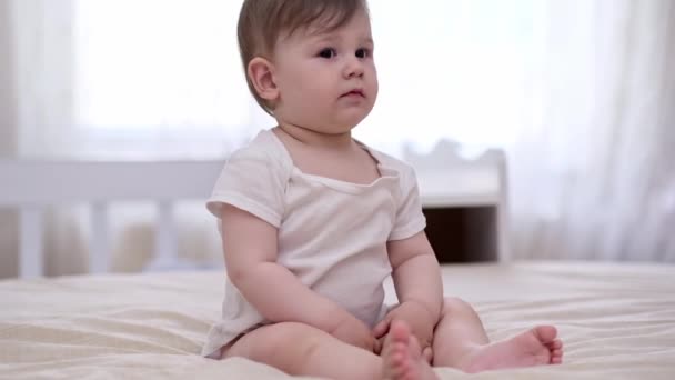 Niedliche Mollige Baby Junge Weißen Body Sitzt Auf Weichem Bett — Stockvideo