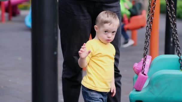 Цікавий Маленький Хлопчик Синдромом Дауна Грає Рожевими Деталями Гойдалок Дбайлива — стокове відео