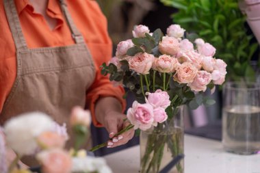 Çiçekçi elleri sanatsal olarak kapanıyor pembe güller ve şakayık çiçekleri birleştiriyor. Güzellik ve zarafet saçan büyüleyici bir buket yaratmak için.