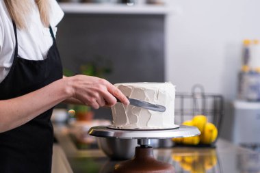 Profesyonel pastacı, pastaya beyaz şekersiz makarna serpiştiriyor. Bıçaklı, önlüklü kadın, mutfakta bekleyen müşteriler için lezzetli organik hamur işleri yapıyor.