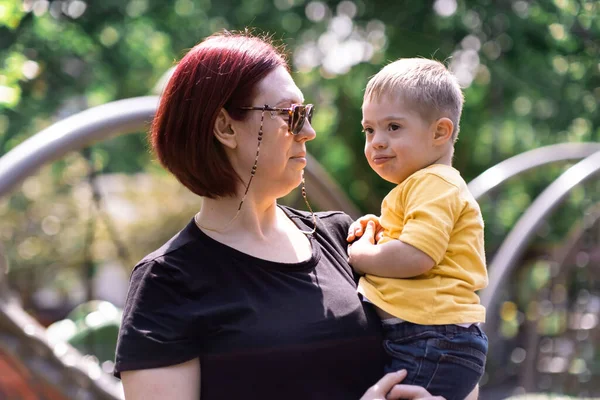 Kochająca Matka Okularach Przeciwsłonecznych Patrząc Małego Syna Zespołem Downa Ramionach — Zdjęcie stockowe