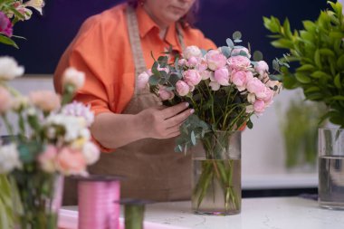 Kadın girişimci ve çiçek dükkanının sahibi küçük iş dünyasındaki başarısının bir yansıması olan bir buket çiçekle güvenle ayakta duruyor.