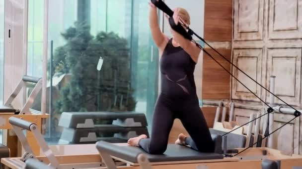 Young Blonde Woman Stretching Arms Back Reformer Modern Pilates Studio — Stock Video