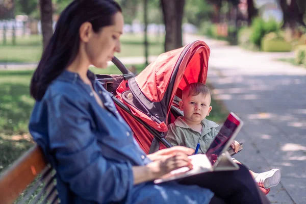 Ciekawy Mały Syn Patrząc Matkę Wpisując Klawiaturze Laptopa Siedzi Wózku — Zdjęcie stockowe
