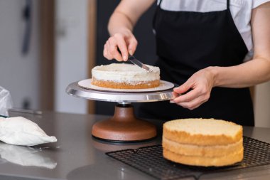 Ev hanımının modern mutfağındaki masada bıçakla organik pasta katmanları süren yetenekli kadın pastacı müşteriler için lezzetli yemekler pişirmekten zevk alıyor.