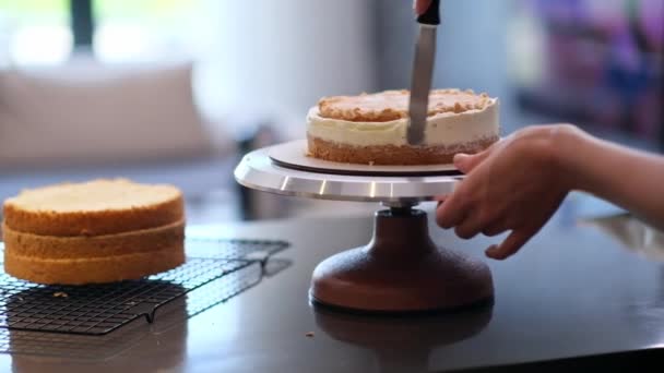 在无乳糖产品制成的蛋糕层周围 熟练的自制糖果店抹布白色奶油站在厨房桌旁 用专业的器皿制作手工糕点特写 — 图库视频影像